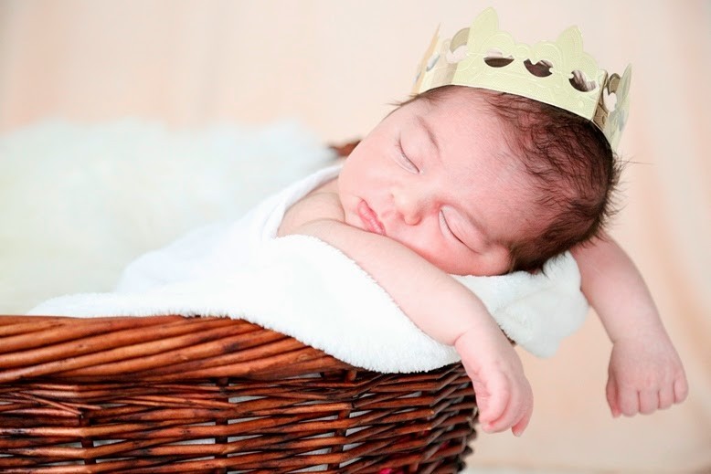 Baby Emin liegt mit Krone auf dem Kopf in einem Korb