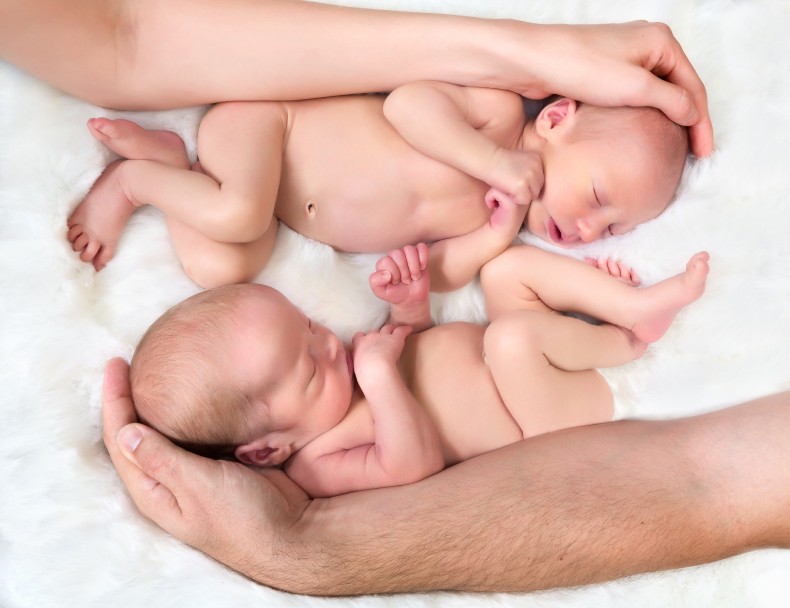 Neugeborene Zwillinge in den Armen von Vater und Mutter
