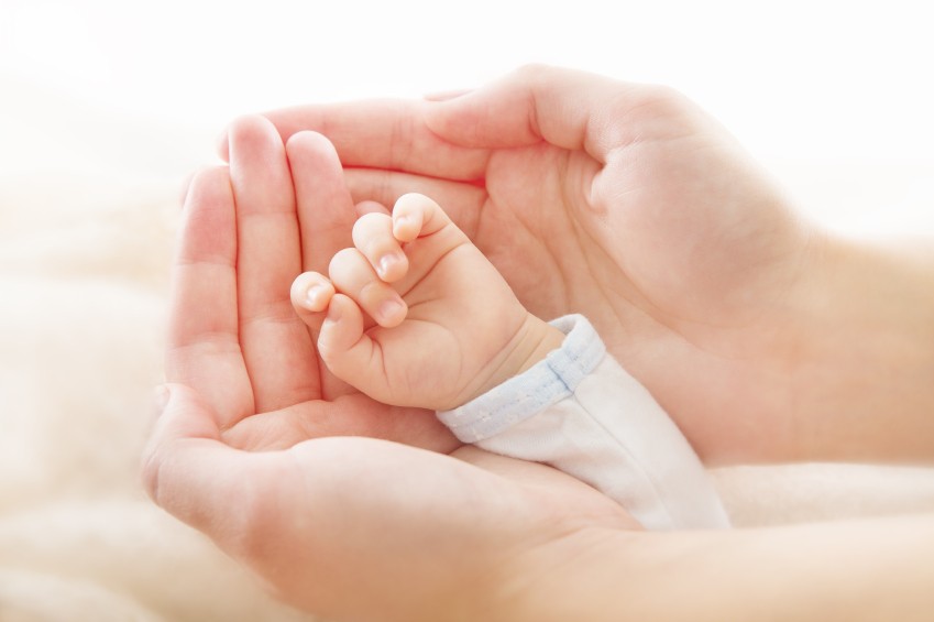 Neugeborenenhand in Händen der Mutter